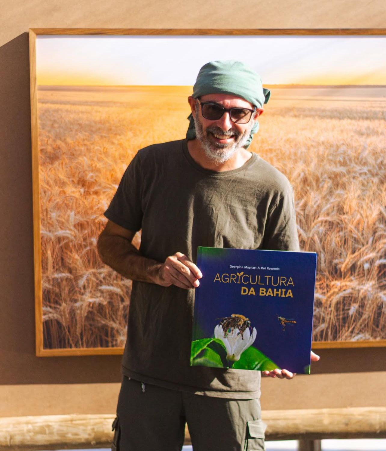 Rui Rezende em seu estúdio, segurando o livro Agricultura da Bahia